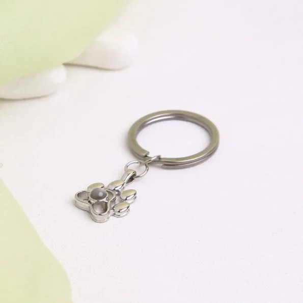 Paw-shaped projection keychain with hidden photo, festive and emotional Christmas gift for pet owners.