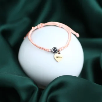 Rope bracelet with heart charm, hidden photo, and engraved name or date option.
